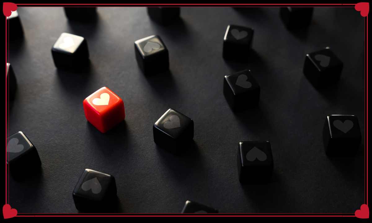 Red die with heart pattern surrounded by black dice on a dark surface