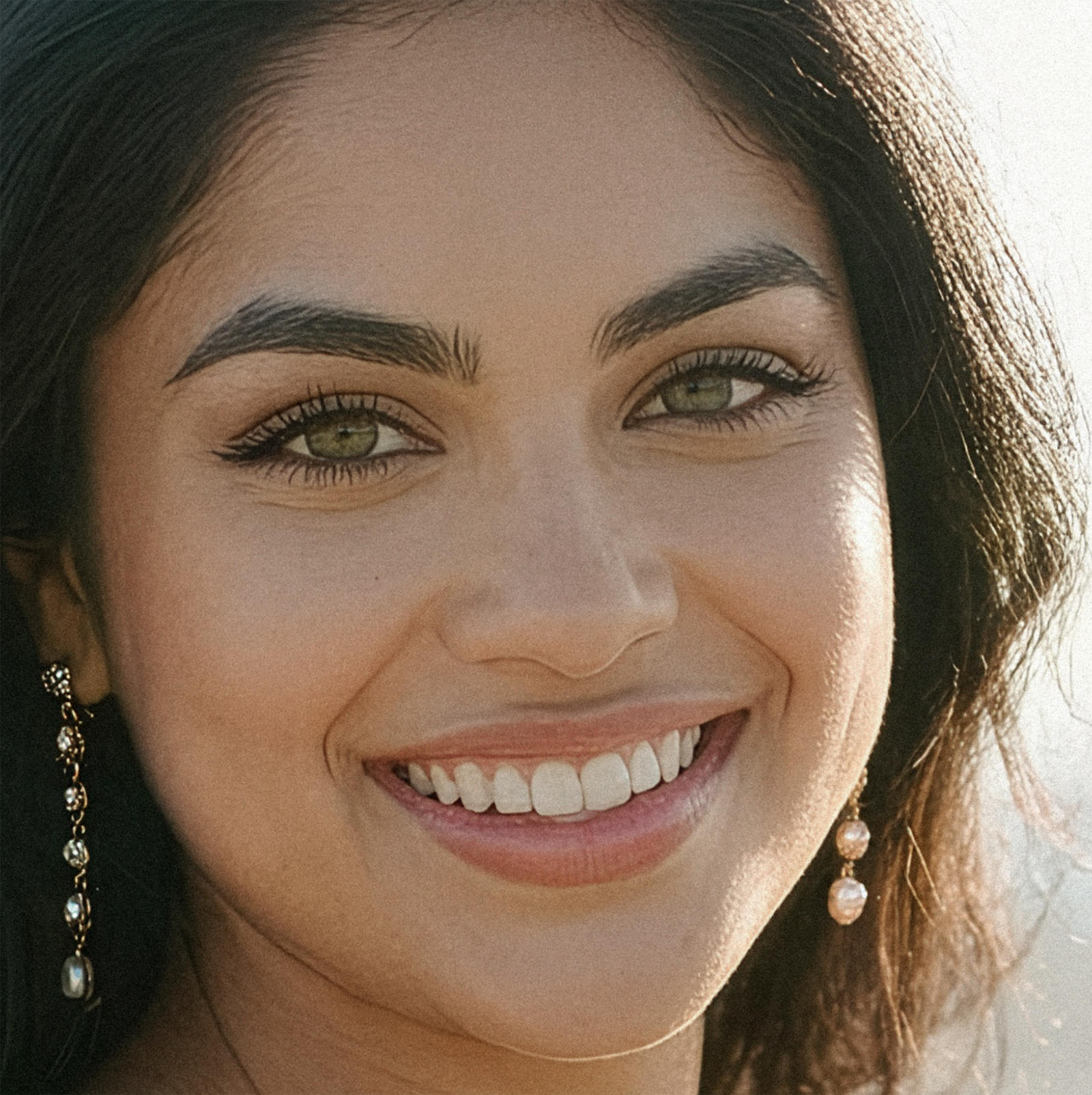A close-up photo of Judith smiling at the camera, her green eyes sparkling, standing in front of the ocean wearing a burgundy dress.