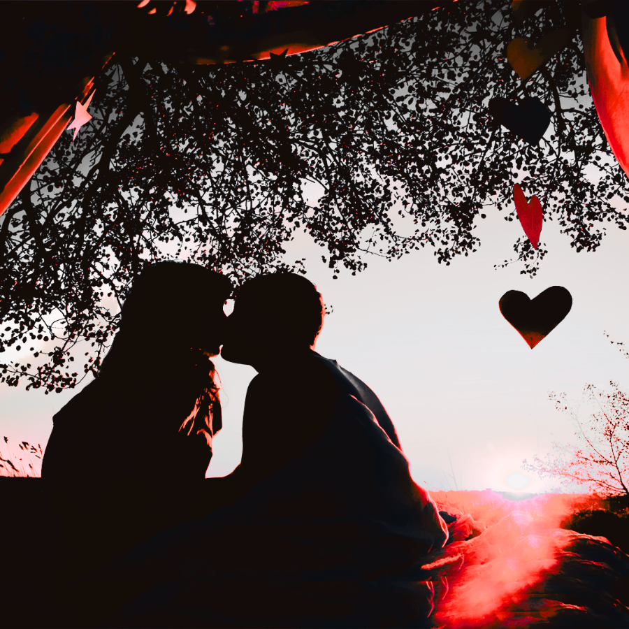 Silhouette of a couple sitting under a tree with heart decorations, creating a romantic atmosphere.